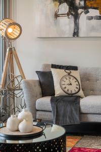 a living room with a couch and a clock on a table at Astra Apartments Newcastle (Merewether) in Merewether