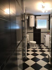 a bathroom with a toilet and a black and white checkered floor at Villa Ceki in Zadar