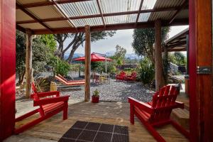 a patio with two red chairs and a table at The Factory Luxury Accomodation in Kaikoura