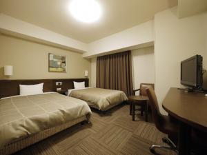 a hotel room with two beds and a desk and a television at Hotel Route-Inn Hisai Inter in Tsu