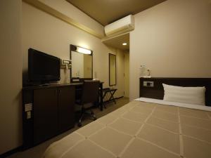 a bedroom with a bed and a desk and a television at Hotel Route-Inn Hisai Inter in Tsu