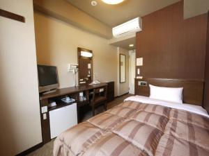 a bedroom with a bed and a desk and a television at Hotel Route-Inn Suwa-Inter2 in Suwa