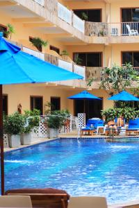 uma grande piscina com guarda-sóis e cadeiras azuis em Baan Boa Resort em Praia de Patong