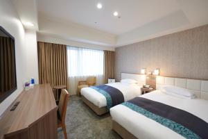 尼崎市にあるホテルヴィスキオ尼崎 by GRANVIAのベッド2台とデスクが備わるホテルルームです。