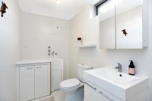 a white bathroom with a toilet and a sink at Esplanade Escape in Aldinga Beach
