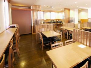a dining room with wooden tables and chairs at Hotel Route-Inn Suwa Inter in Suwa