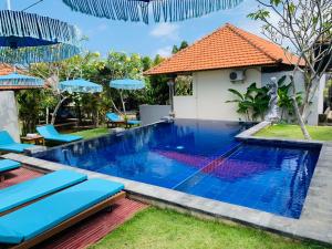 a pool with chairs and umbrellas next to a house at Pandawa Beach Homestay in Uluwatu