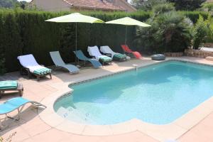 una gran piscina con sillas y sombrillas en La Bastide des Pins, en Le Pradet