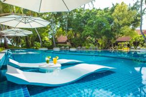 a swimming pool with a table and an umbrella at Niva Kurumba Maldives in Male City