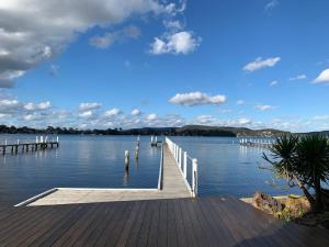 a dock on a lake with a blue sky and clouds at Karoola in Point Clare