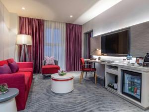 a hotel room with a red couch and a tv at Mercure Hai Phong in Hai Phong
