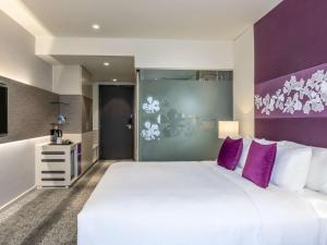 sypialnia z dużym białym łóżkiem i fioletowymi ścianami w obiekcie Mercure Hai Phong w Hajfong