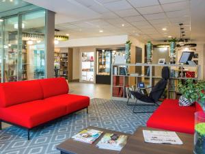 ローザンヌにあるイビス ローザンヌ センターの赤いソファとテーブルが置かれた図書館