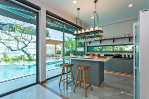 Nong Prue的住宿－Hi At Home Villa 4，享有泳池景致的厨房和2个酒吧凳