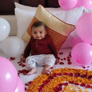 a baby sitting on a bed next to balloons at Wood Stock Kasauli - Rooms & Cottages - Panoramic View & Balcony Rooms in Kasauli