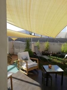 d'une terrasse avec une chaise, une table et un parasol jaune. dans l'établissement lo zahir, à Marina di Ragusa