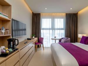 a hotel room with a bed and a tv at Mercure Hai Phong in Hai Phong