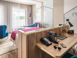 カリーニングラードにあるMercure Kaliningradのベッド、デスク、電話が備わるホテルルームです。
