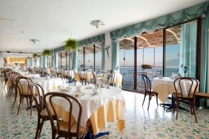 una sala da pranzo con tavoli, sedie e finestre di Hotel Settimo Cielo a Sorrento