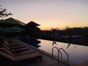 a resort swimming pool with a sunset in the background at Gubug Balian Beach Bungalow in Selemadeg
