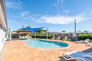 Una piscina en un patio con sillas y un cielo azul. en Holiday Haven Burrill Lake, en Burrill Lake