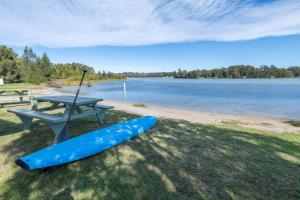 a picnic table and a paddle board next to a lake at Holiday Haven Burrill Lake in Burrill Lake