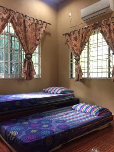 2 camas en una habitación con 2 ventanas en Homestay Cikgu Sungai Batu Besi, en Bedung