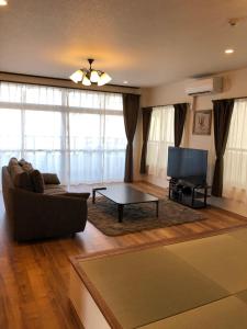 ein Wohnzimmer mit einem Sofa und einem Flachbild-TV in der Unterkunft Amami Weekly House Nico Nico Nazeko-ten in Amami