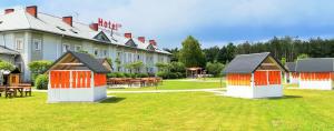 un hôtel avec des tables et des bâtiments orange et blancs dans l'établissement Hotel TIREST, à Grebiszew