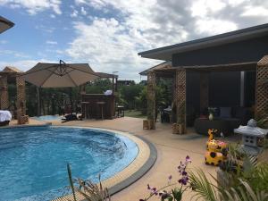 ein Swimmingpool mit Sonnenschirm neben einem Haus in der Unterkunft SB Holiday Resort Chiang Mai in Chiang Mai + 32 Fotos