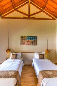 two beds in a room with wooden ceilings at Nativo Lombok Hotel in Kuta Lombok