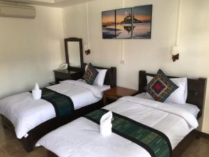 three beds in a room with white sheets at Jasmine Vangvieng Hotel in Vang Vieng