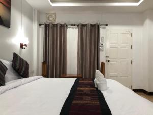 a bedroom with a large white bed and a door at Jasmine Vangvieng Hotel in Vang Vieng