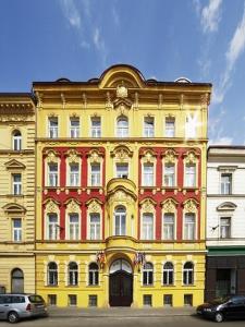 un edificio amarillo y rojo con coches estacionados frente a él en Hotel Otakar en Praga