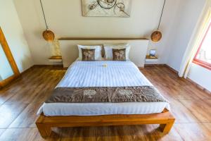 a bedroom with a large bed with wooden floors at Nativo Lombok Hotel in Kuta Lombok