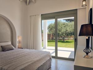 a bedroom with a bed and a sliding glass door at Gerakas Luxury Villas in Vasilikos
