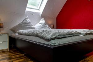 uma cama num quarto com uma parede vermelha em Moselglück em Sankt Aldegund