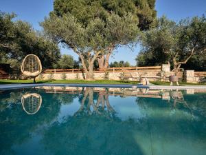 a swimming pool with two chairs and a table and trees at Gerakas Luxury Villas in Vasilikos