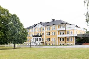 duży żółty budynek z drzewem przed nim w obiekcie Tyringe Kurhotell w mieście Tyringe