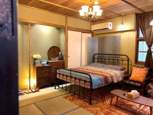a bedroom with a bed and a chair in a room at Machiya Hinoki in Tainan