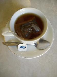 a cup of coffee on a plate with a spoon at Trawangan Cottages in Gili Trawangan