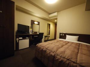 Pokój hotelowy z łóżkiem i biurkiem w obiekcie Hotel Route-Inn Hofu Ekimae w mieście Hofu