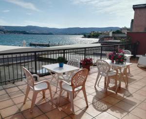 a patio with two tables and chairs and the water at Hotel La Bussola in Muggia