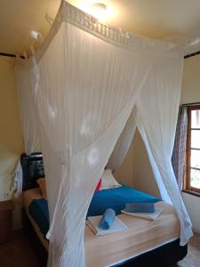 Bett mit Baldachin in einem Zimmer in der Unterkunft Arnel Bungalows in Senggigi 