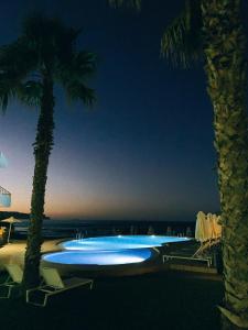 a swimming pool with chairs and palm trees at night at Phaedra Hotel in Stalos