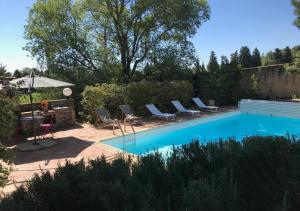 a swimming pool with chairs and a table and an umbrella at Au Coeur des Vignes en Provence in Châteauneuf-de-Gadagne