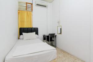 a bedroom with a white bed with a black headboard at Lestari Guesthouse in Padang