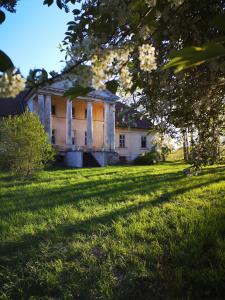 an old house in the middle of a grass field at Padures muiža in Padure