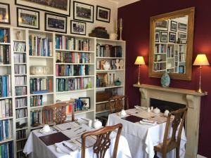 a dining room with two tables and bookshelves at Ashbury Bed & Breakfast in Great Malvern