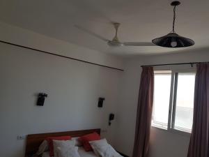 a bedroom with a bed with a ceiling fan and a window at Hotel Le Relais Normand in Antananarivo